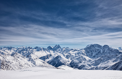 Man standing on the top of a snowcapped mountain peak. Panoramic view.