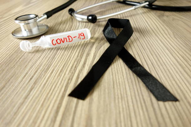 Mourning ribbon, ampoule with text Covid-19 and stethoscope. Coronavirus death victim concept Mourning ribbon ampoule with text Covid-19 and stethoscope on doctor office desk. Coronavirus death victim concept dead stock pictures, royalty-free photos & images