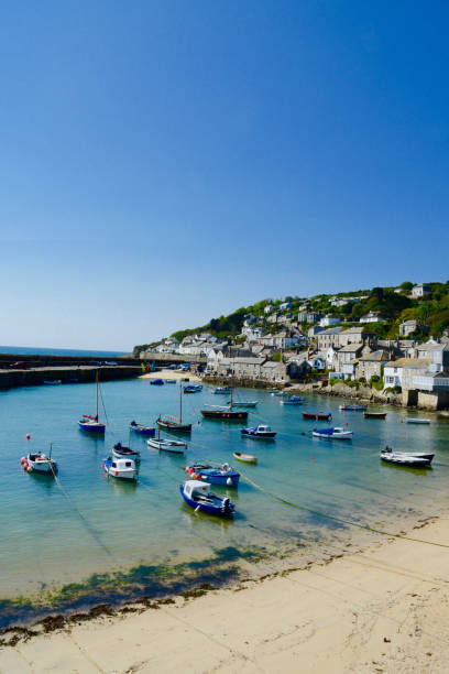 Mousehole village harbour, Penzance, Cornwall, UK Mousehole has a small harbour beach inside its wall. Mousehole is where stargazey pie was invented and home to the famous Christmas lights fishing village stock pictures, royalty-free photos & images
