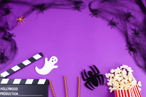 Movie Clapper board in spider webs, spiders, ghost, eyes on purple Lilac Background. stock photo