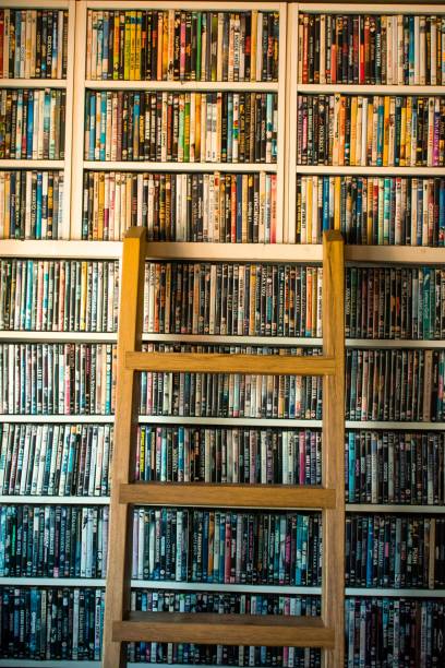 Movie collection on a shelf Movies in DVD cases on a shelf and a ladder used as decoration for a pub dvd stock pictures, royalty-free photos & images