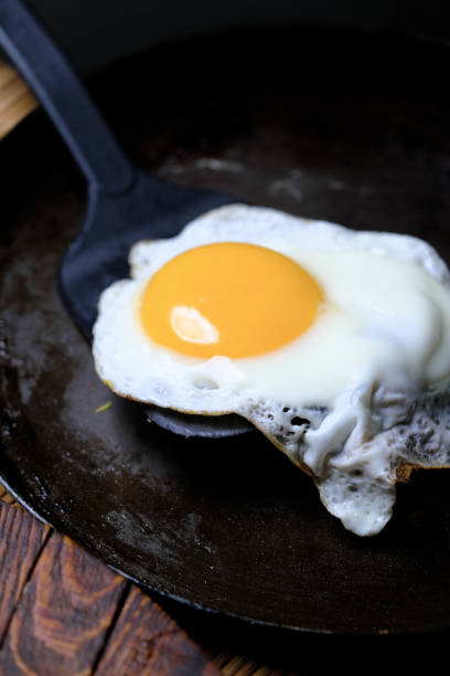 Moving a fried egg from frying pan stock photo