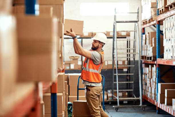 Moving and storing new stock Shot of a young man working in a warehouse picking up stock pictures, royalty-free photos & images