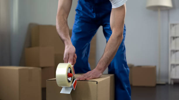 Moving company worker packing cardboard boxes, quality delivery services stock photo