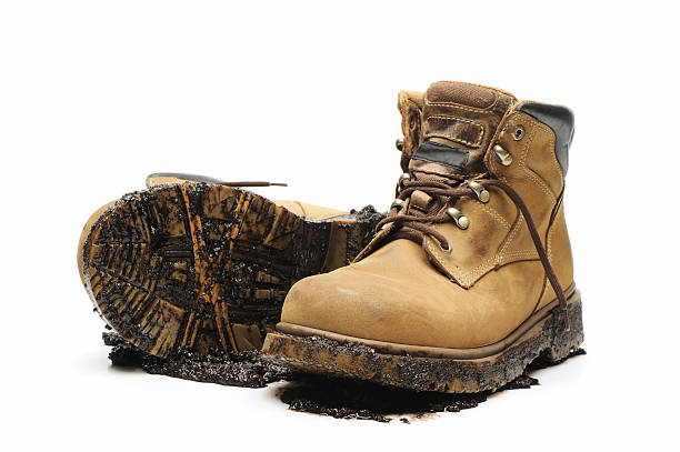 Muddy and dirty work boots on white background stock photo