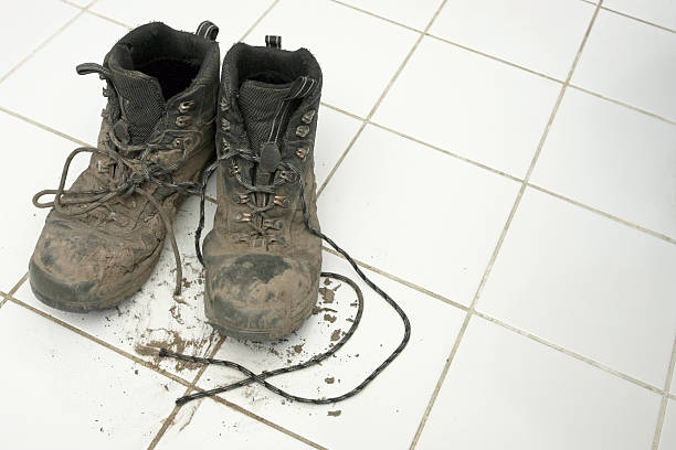 muddy hiking boots leaving dirt on clean white tiles - muddy shoes stockfoto's en -beelden
