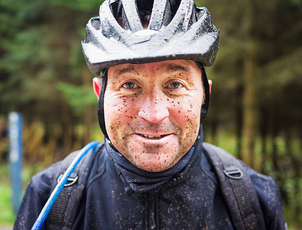 A man's face covered in muddy spots after a mountain biking session.