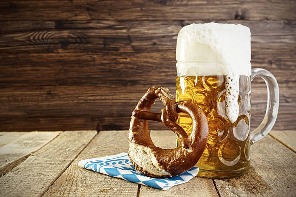 mug of beer and a soft pretzel on a table - duits bier stockfoto's en -beelden
