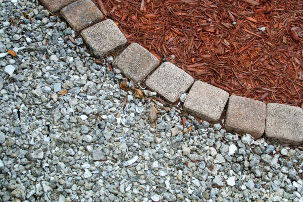 mulch gravel and brick background Looking down at square bricks form curve that separates mulch from gravel or small stones in backyard garden area with copy space. mulch stock pictures, royalty-free photos & images