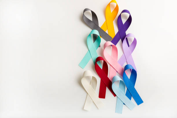 multi colored cancer ribbons proudly worn by patients, supporters and survivors for world cancer day. bringing awareness to all types of cancer - world cancer day imagens e fotografias de stock