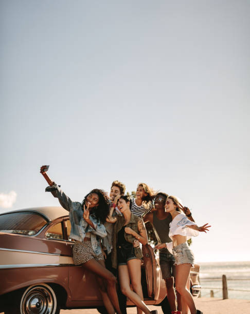 Multi ethnic friends taking a selfie near the car Group of multi ethnic people taking a selfie near the car. Young men and women together on road trip making selfie. road trip photos stock pictures, royalty-free photos & images