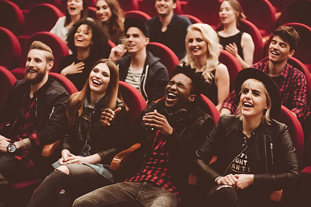 Multi ethnic group of young people in the cinema or theater, watching, laughing. 