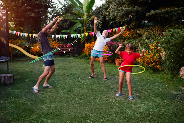 multi generatie familie hula hooping in achtertuin - family garden,party stockfoto's en -beelden