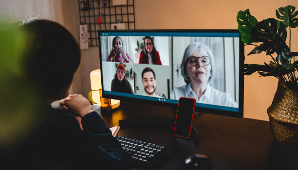 Multi generational business woman having video call with colleagues using computer app - Focus on mobile phone stock photo