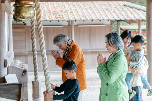 Multi- generational family praying at a Japanese temple. Okayama, Japan