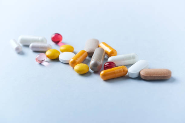 Multicolor vitamins and supplements on bright paper background. Concept for a healthy dietary supplementation. Copy space. Multicolor vitamins and supplements on bright paper background. Concept for a healthy dietary supplementation. Close up. pill stock pictures, royalty-free photos & images