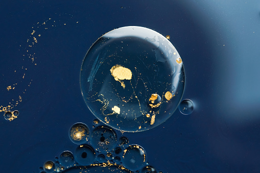 Gold and blue acrylic paint bubbles move and explode in the water