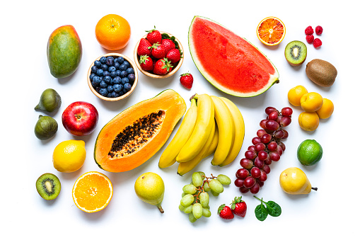 Overhead view of multicolored fresh ripe organic fruits shot on white background. The composition includes mango, orange, strawberry, blueberry, kiwi, peach, grape, watermelon, banana, papaya, apple, pear, fig, lime and lemon. High resolution 42Mp studio digital capture taken with SONY A7rII and Zeiss Batis 40mm F2.0 CF lens