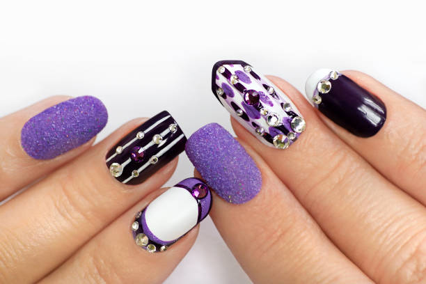 Multi-colored manicure with white and lilac varnish on various forms of nails stock photo