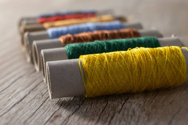multi-colored threads on a light wooden background. - linha artigo de costura imagens e fotografias de stock