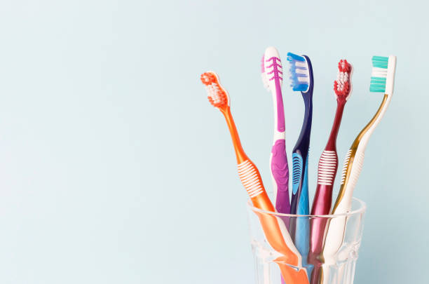 Multi-colored toothbrushes in a glass cup, blue background stock photo