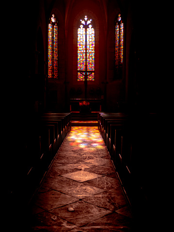 Abstract multicolor glassworks of Saint-Côme-d'Olt church in France seen from inside with no people and with projection of the glasswork colors on the church floor