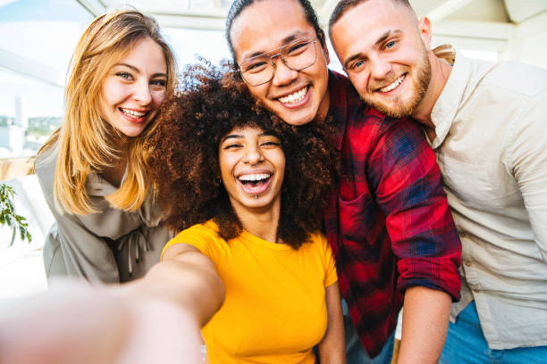 Multicultural group of friends taking a selfie with african woman in foreground - Friendship concept with young people smiling at camera - Focus on black girl stock photo