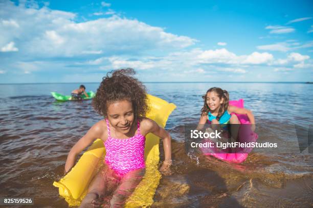 multicultural happy girls swimming on inflatable mattresses at sea together