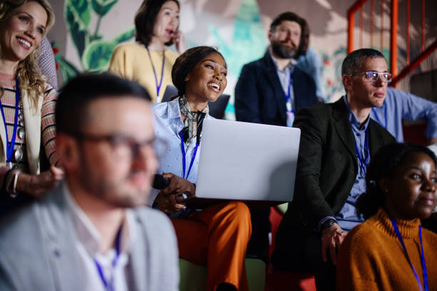 Multi-ethnic audience sitting in an amphitheater while listening to presentation at conference stock photo