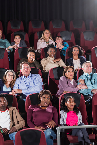 Multiethnic Audience Watching Scary Movie In Theater Stock Photo