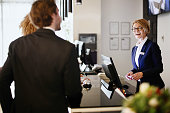 istock Multi-ethnic business couple arriving at hotel reception desk 1374474070