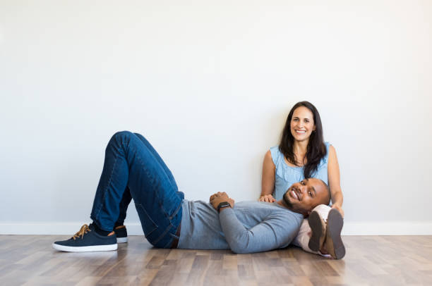 Multiethnic couple at home Young multiethnic couple relaxing on floor and looking at camera with copy space. Happy african man resting on the leg of his girlfriend after move house. Black guy lying on ground with her wife in new home. cougar woman stock pictures, royalty-free photos & images