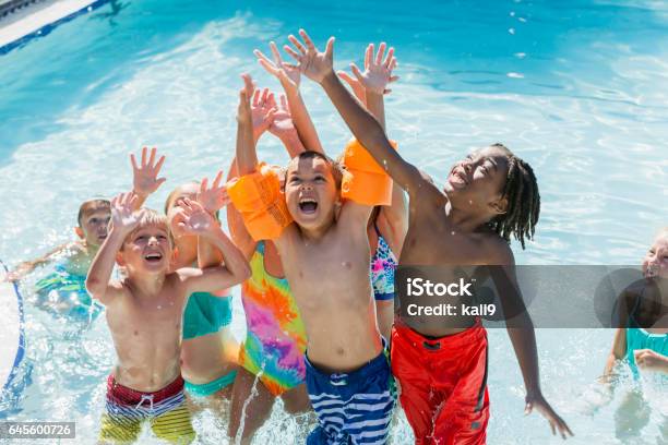 Multi-ethnic group of children playing in swimming pool