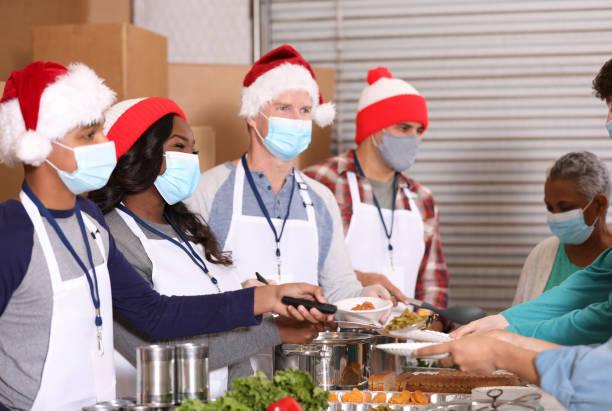 Multi-ethnic group of volunteers work at soup kitchen at Christmas. stock photo