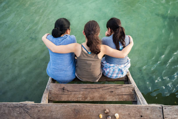 Multi-Ethnic Mother and Daughters Gazing at Water from Dock Stairs Asian mom and Eurasian daughters in Punta Laguna Nature Reserve, Tulum, Yucatan Peninsula, Quintana Roo, Mexico mexican teenage girls stock pictures, royalty-free photos & images