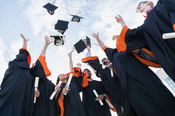 Multi-ethnic teenage graduates throw caps in air A group of seven multi-ethnic high school or university graduates wearing graduation gowns, holding diplomas. Throwing their caps in the air. public universities in usa stock pictures, royalty-free photos & images
