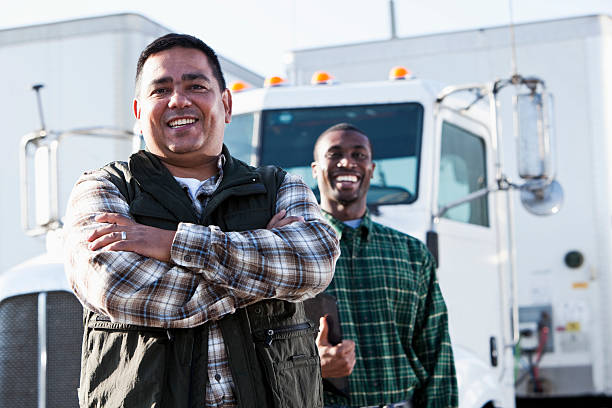Multi-ethnic truck drivers Hispanic and African American truck drivers standing in front of semi-truck.  Focus on Hispanic man (40s). truck driver stock pictures, royalty-free photos & images