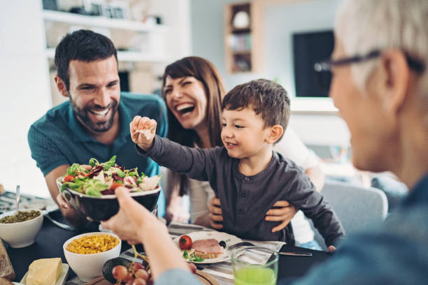 mehrgenerationenfamilie beim gemeinsamen mittagessen - essen mund benutzen stock-fotos und bilder