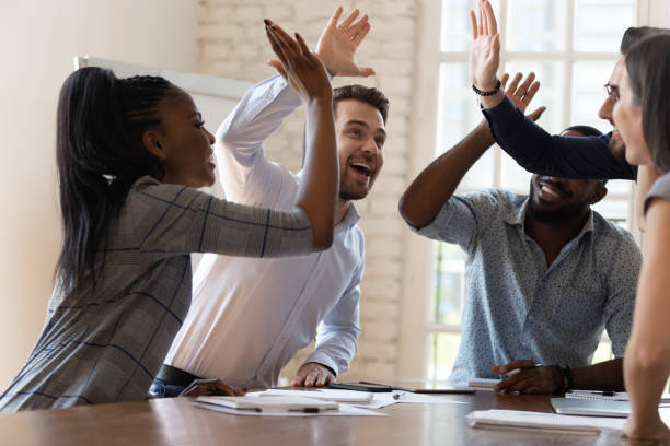 multiracial euphorische business-team-mitarbeiter geben hohe fünf im amt - motivation stock-fotos und bilder