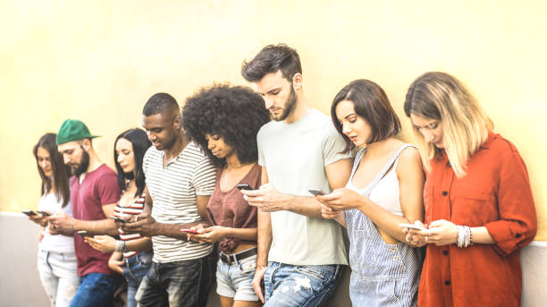Multiracial friends using mobile smartphone at university coampus - Millenial people addicted by smart phones - Tech concept with always connected millennials on social networks - Bright warm filter  generation z stock pictures, royalty-free photos & images
