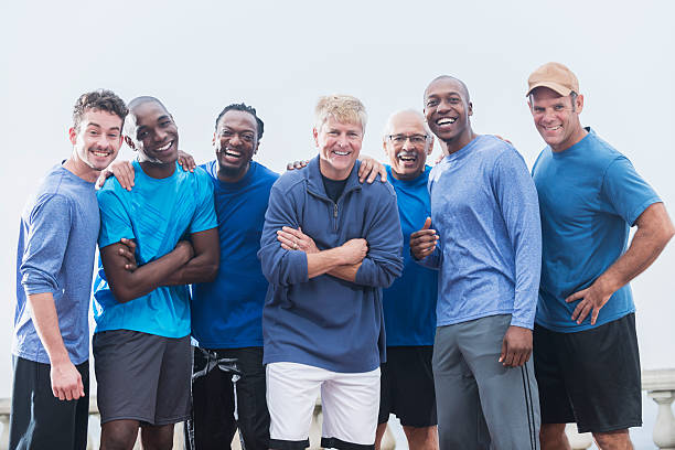 Multiracial group of men wearing blue shirts Diverse group of men wearing casual blue shirts, standing together outdoors.  Mixed ages, 20s to 70s.  They are confident and happy, smiling at the camera. only men stock pictures, royalty-free photos & images