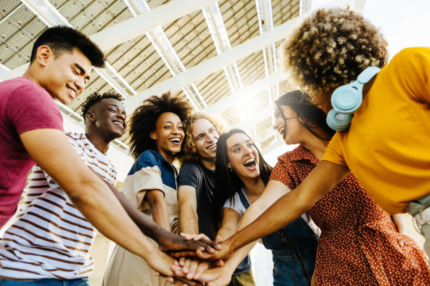 Multiracial happy friends with hands in stack. Multi-ethnic diverse group of college students joining their hands. Stacking hand concept, community, unity and teamwork concept stock photo