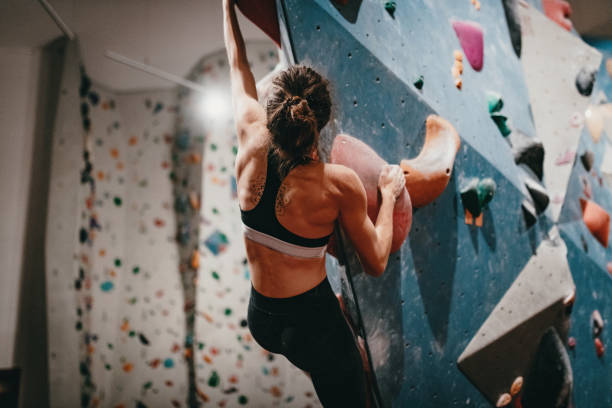 Muscular woman on boulder climbing training Boulder climbing is popular hobby or sport among millennial generation. Mixture of tactics, strength, stamina and determination are crucial for boulder climbing. Photo taken in Berlin, Germany. bouldering stock pictures, royalty-free photos & images