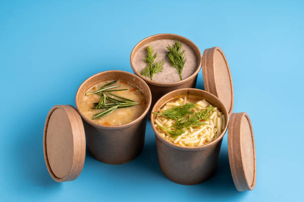 Mushroom, chicken and pea soups in paper disposable cups for take-out or delivery of food on blue background. stock photo