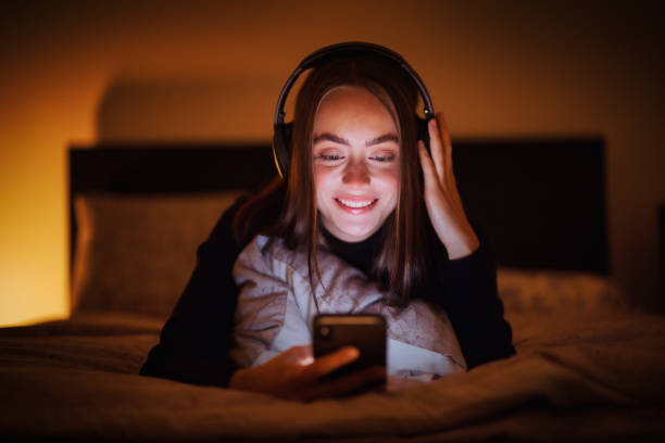 Music first, Happy Teenage Woman lying on Bed with Wireless Headphones night listening music stock pictures, royalty-free photos & images