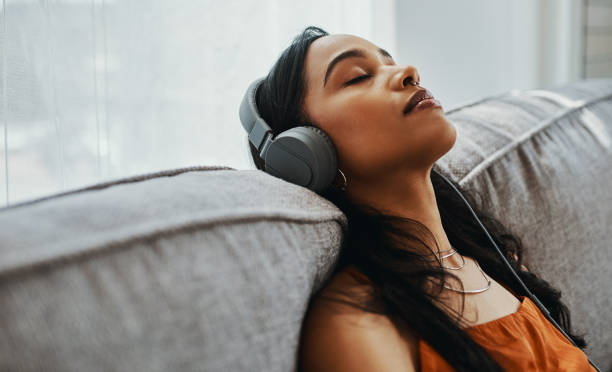 Music first, life later Shot of a young woman using headphones while relaxing on the sofa at home relaxation stock pictures, royalty-free photos & images