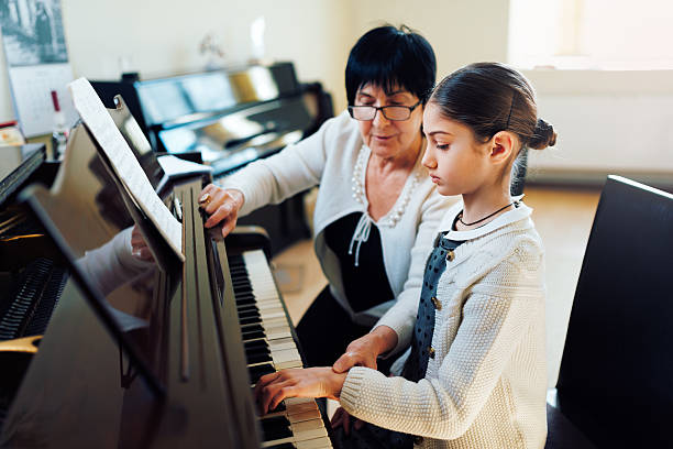 music teacher with the pupil at  lesson piano stock photo