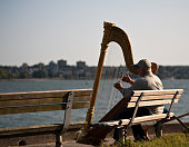 Vancouver, Canada - June 26,2009 : Musician harpist performer sit on a bench near the sea in Vancouver, Canada