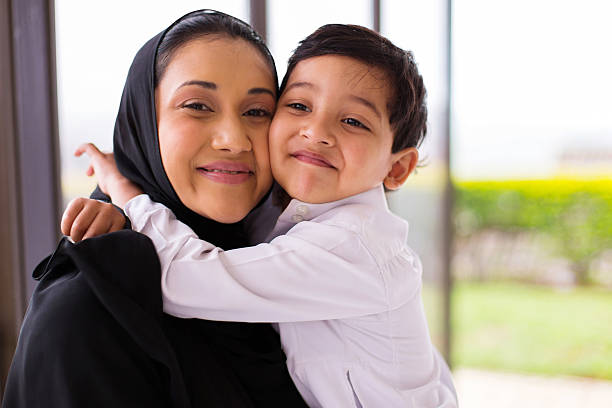 muslim boy hugging his mother stock photo