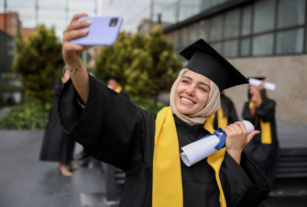 muslim graduate student taking a selfie with her diploma on her graduation day - arabic student stockfoto's en -beelden